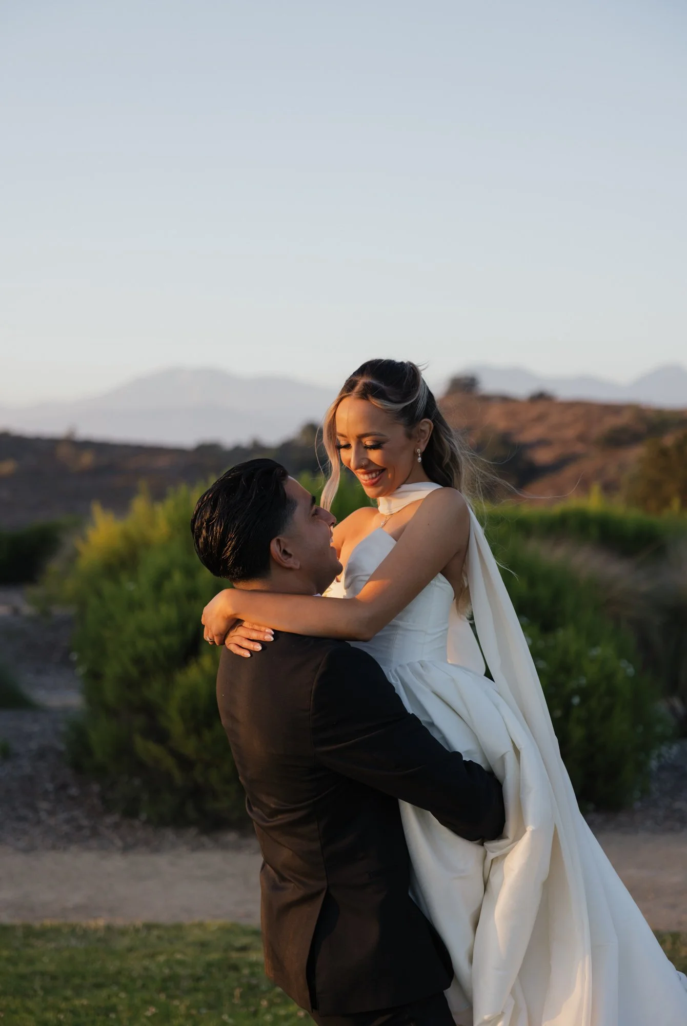 Editorial photographer takes candid photo of bride and groom during their wedding at golden hour in Southern California.