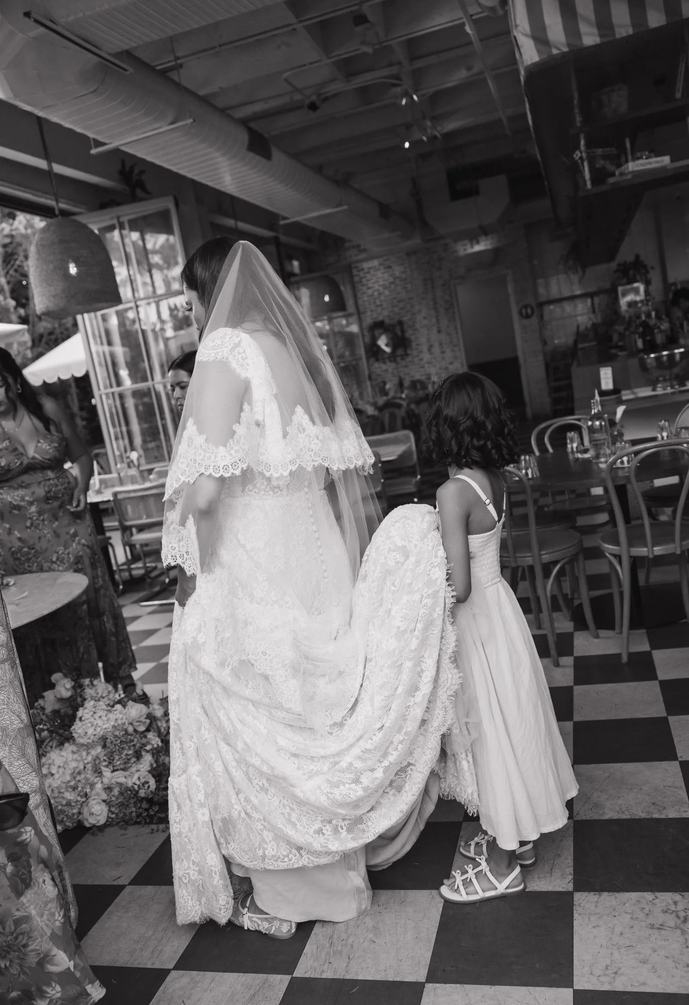 A candid photographer takes a candid photo of a little girl holding brides dress on her wedding day in Los Angeles California.