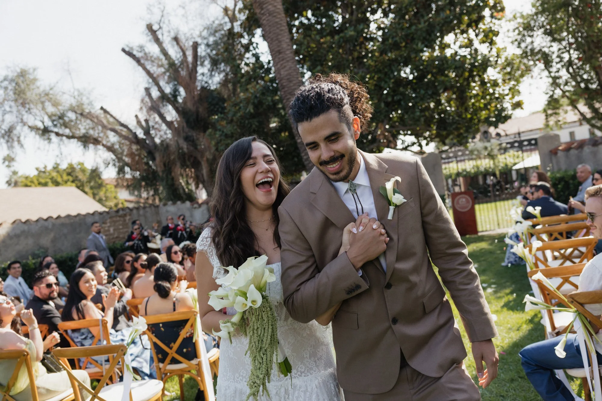 A candid moment as the bride and groom come back down the aisle during their wedding in San Gabriel Mission in Southern California.