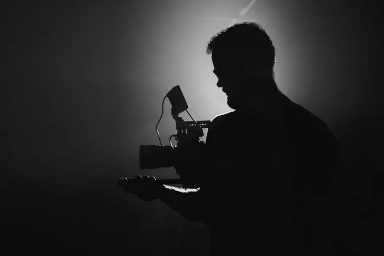 Silhouette of a videographer with a camera in a dark room