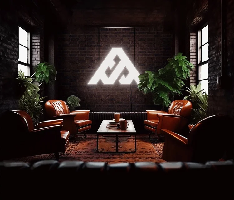 A dark lounge with leather chairs and the All Things Branding mark glowing on a brick wall