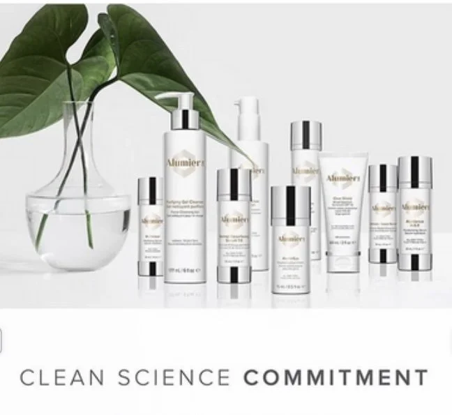 Collection of skincare products from Alchemeier with a large green leaf in a glass vase, arrangement on a white background, with the text "CLEAN SCIENCE COMMITMENT."
