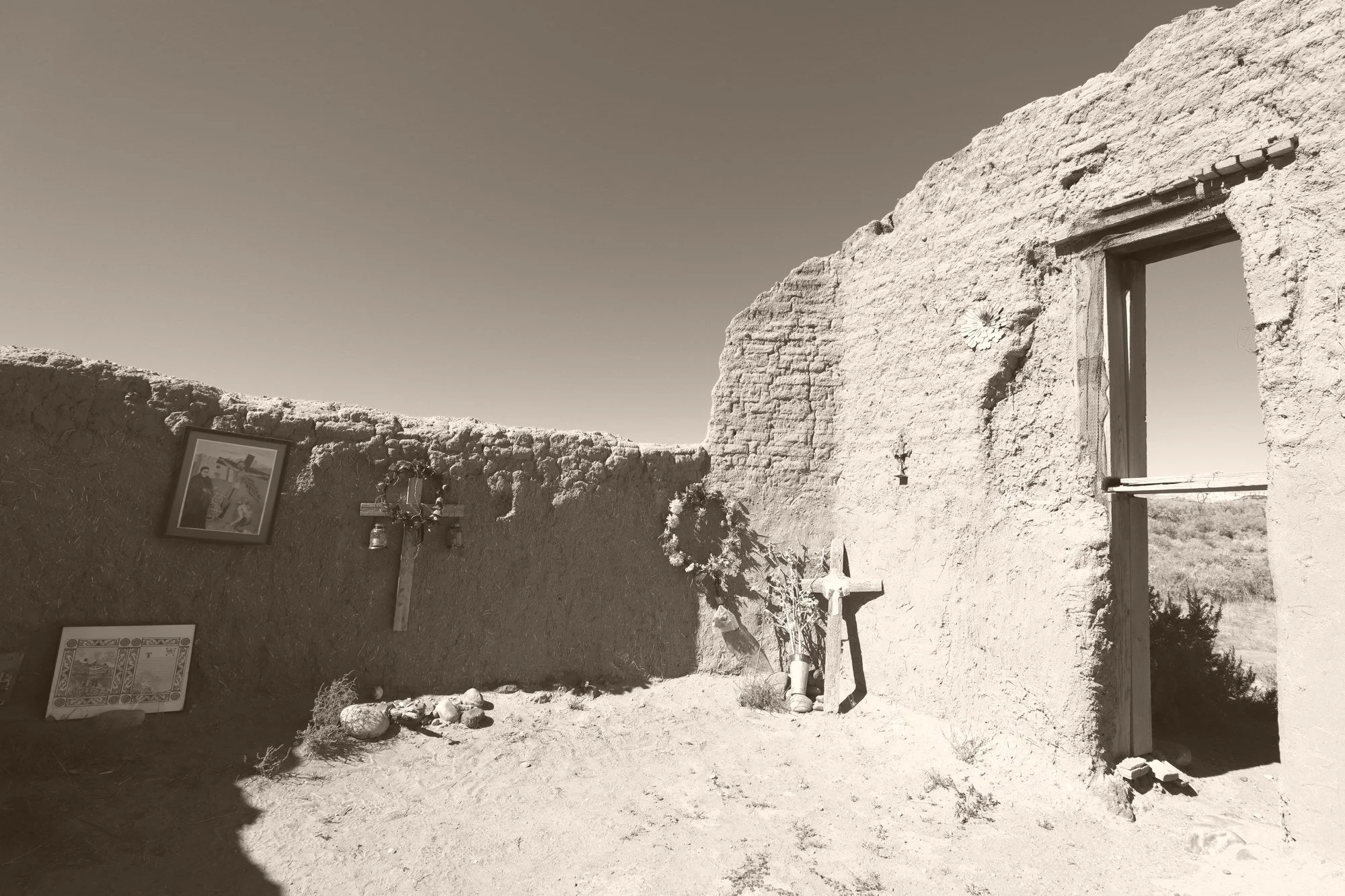 A ruined chapel, still somebody's shrine — crosses, pictures, and offerings in the dust. (New Mexico, Oct 16, 2020)
