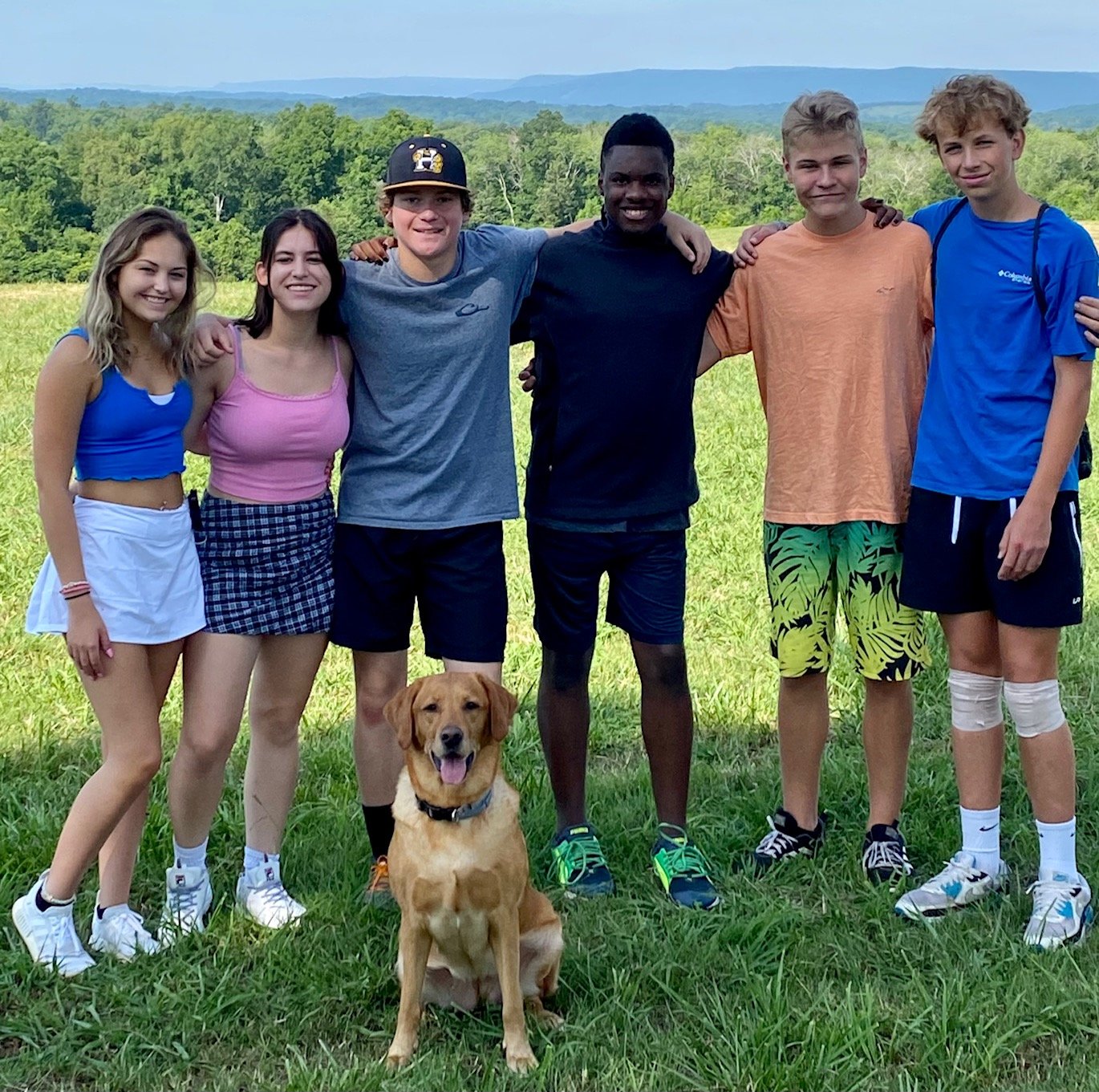 2 girls and 4 boys pose with a golden retriever mix