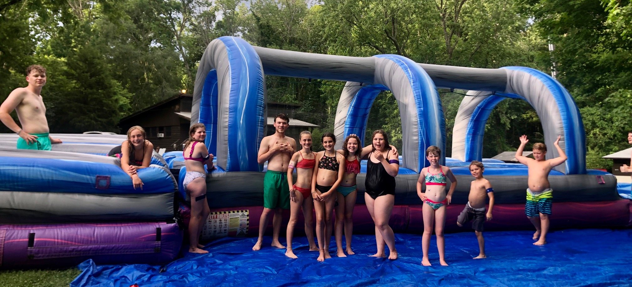 11 campers in bathing suits in front of a blow-up blue water slide