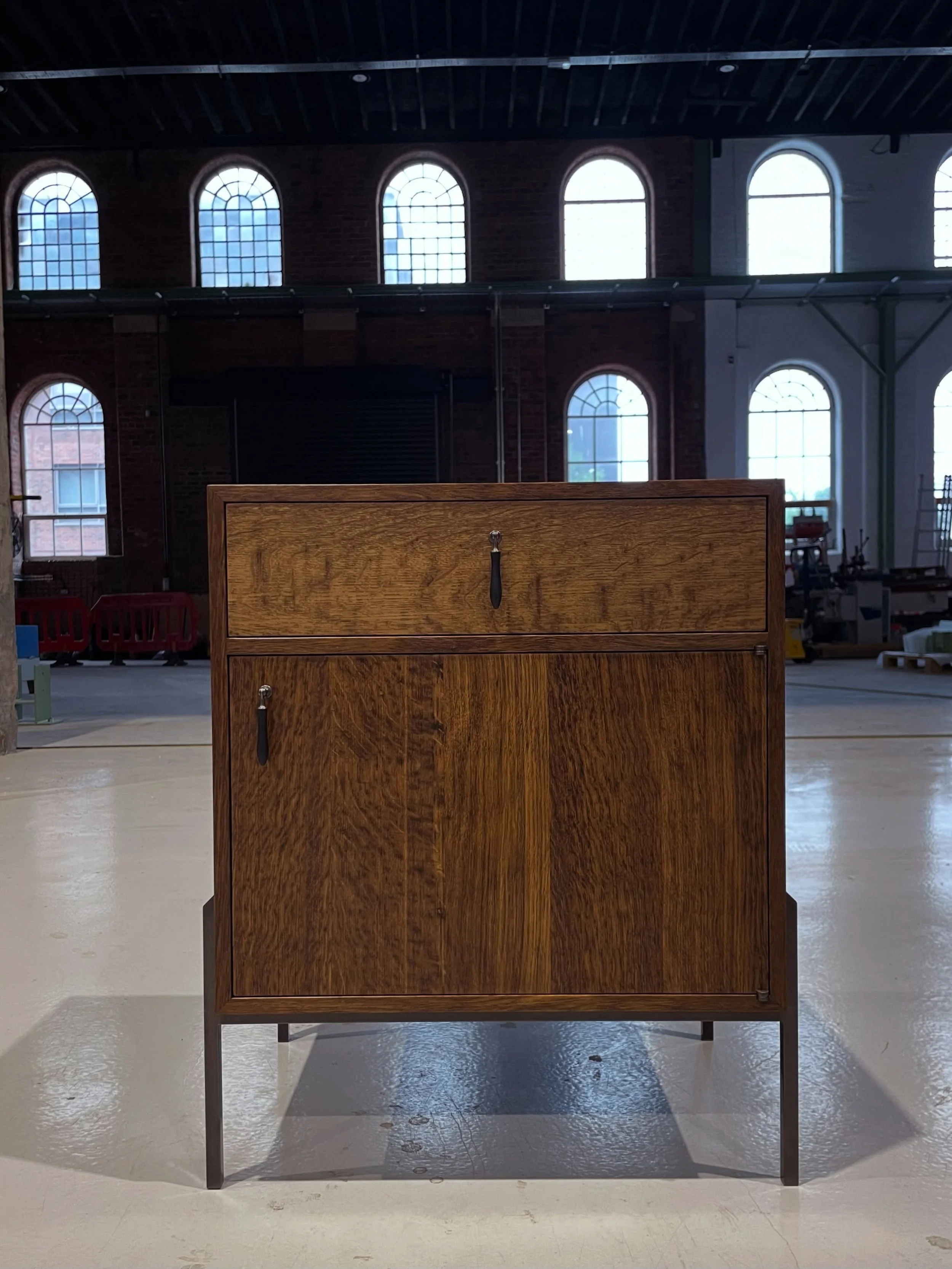 Introducing the Mion nightstand cabinet.

Designed with a little extra space for life&rsquo;s most treasured belongings.The Mion nightstand combines timeless craftsmanship with understated elegance.

A fumed Brown Oak cabinet rests gracefully on a bl