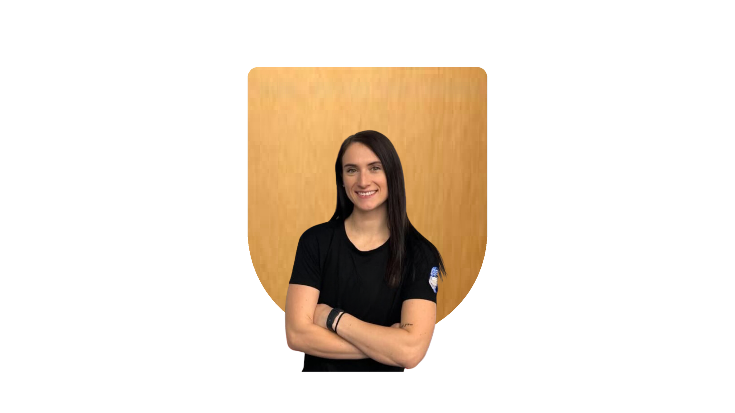 Smiling person with long dark hair wearing a black T-shirt, arms crossed, standing in front of a wooden-textured shield-shaped background.