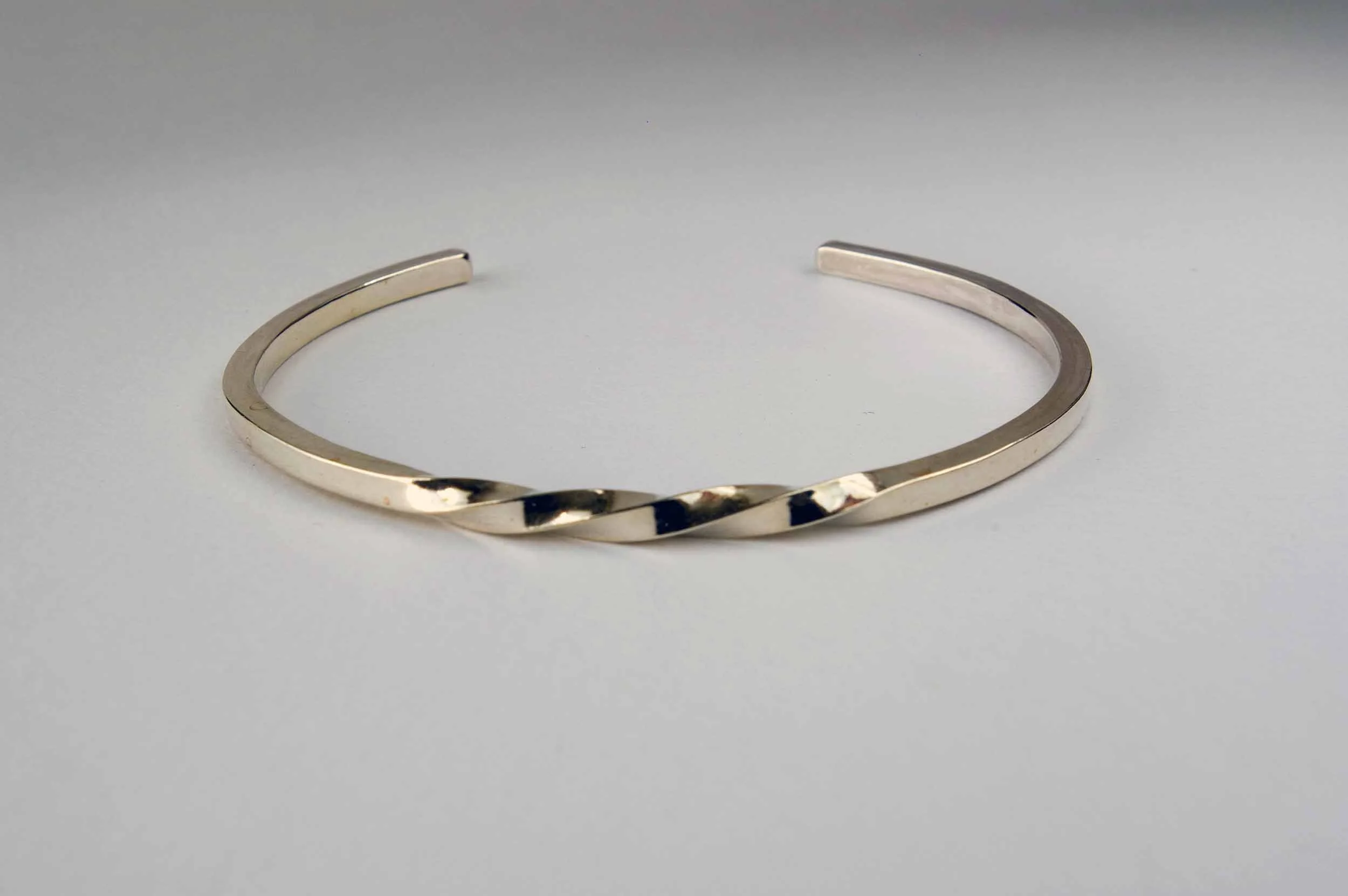 A single thin sterling silver cuff bracelet, measuring 3mm wide, with a three-twist pattern.