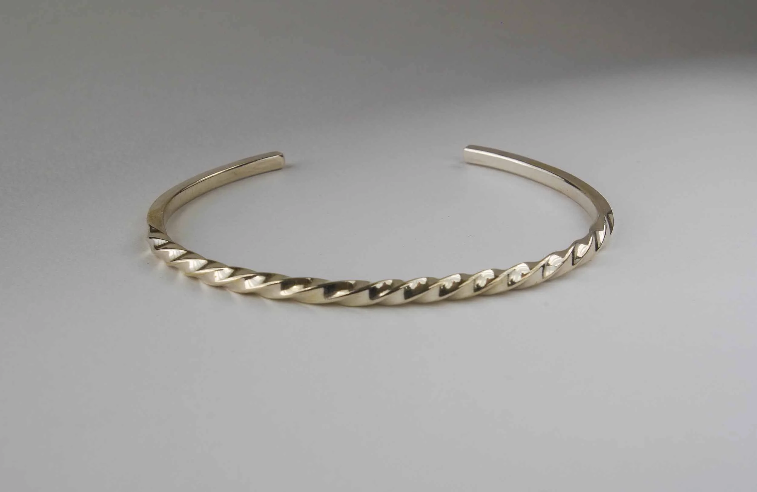 A thin sterling silver cuff bracelet, measuring 3mm wide, with multiple twist pattern.