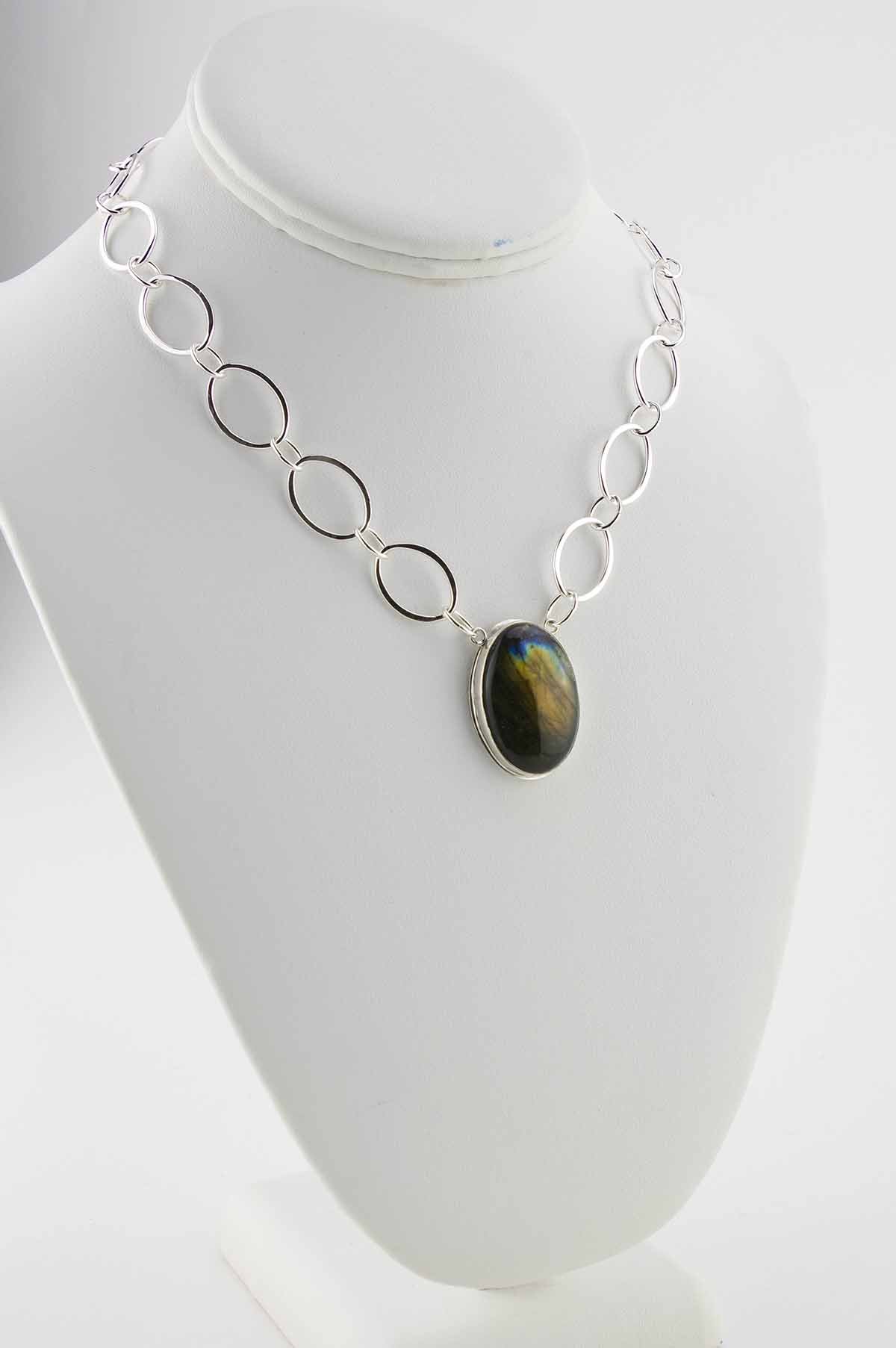 Oval labradorite with orange flash in horizontal setting on a hand-fabricate oval sterling silver chain.
