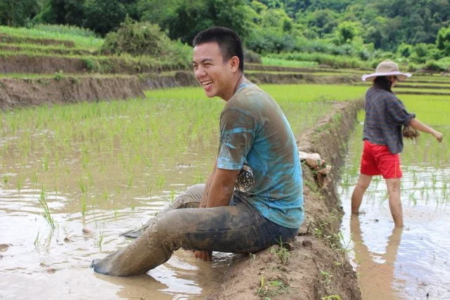 Asian missionary sitting in rice paddy