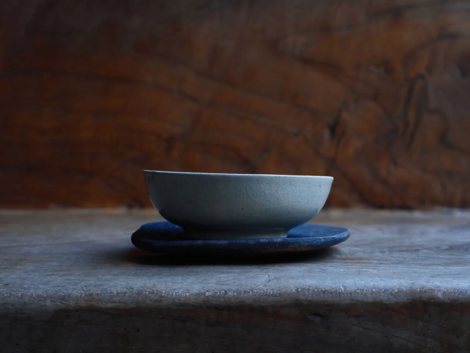 Vietnamese Lê Period vessel with a smooth, light glaze displayed on a contemporary Japanese ceramic tray, highlighting contrast in texture and color.