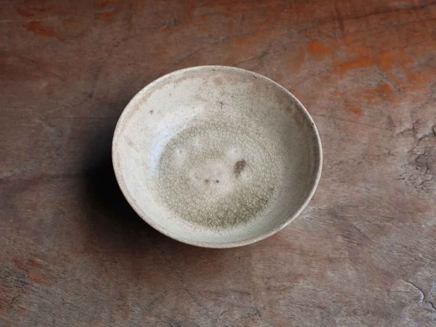 Close-up of a single cup from Le Vietnam Period with a distinctive crackle glaze and gentle undulating rim, photographed from above