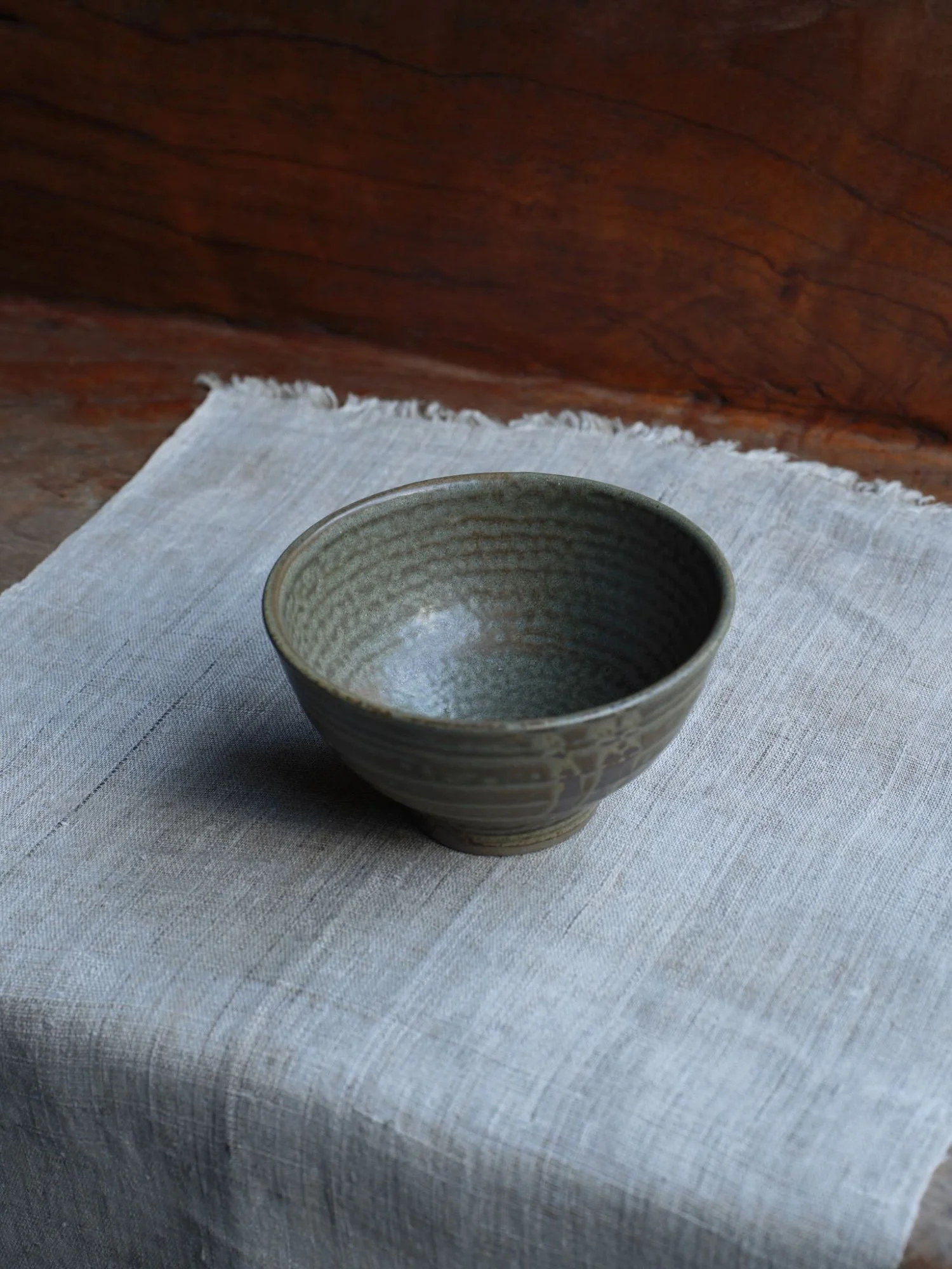 Single textured Japanese pottery bowl with delicate spiral pattern, displayed on pale cloth