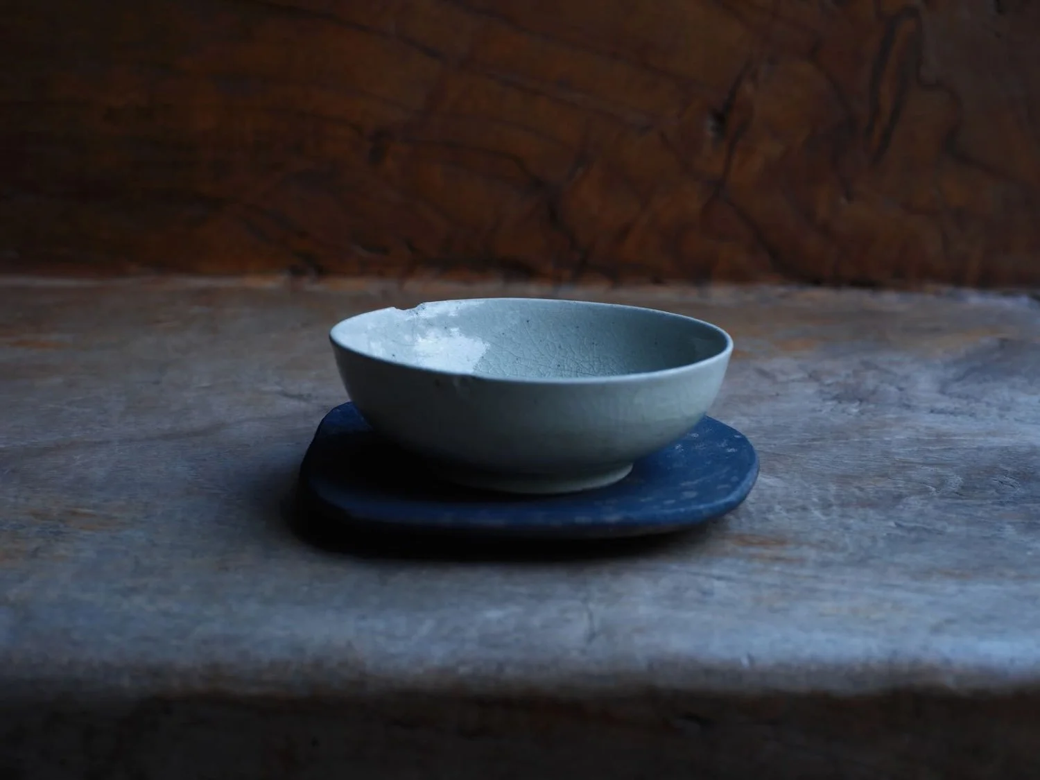 Handmade Vietnamese ceramic vessel with bright glaze paired with dark, textured Japanese pottery tray by Yoshimitsu Ishihara
