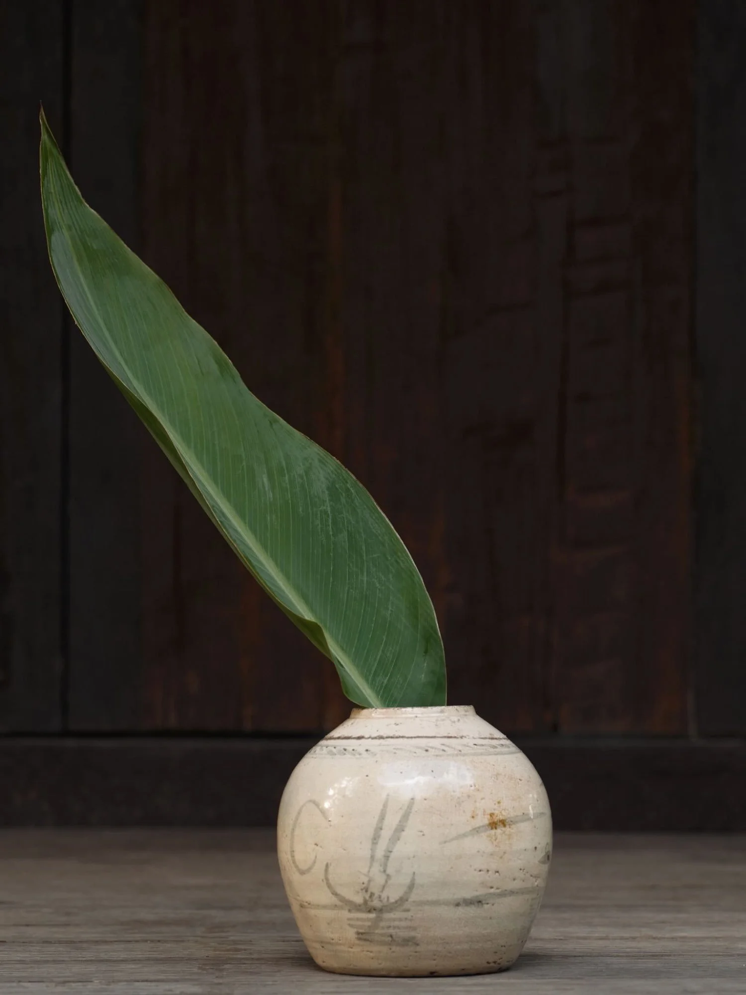 East Asia stoneware vase with a single green leaf, minimalist Japanese-inspired arrangement