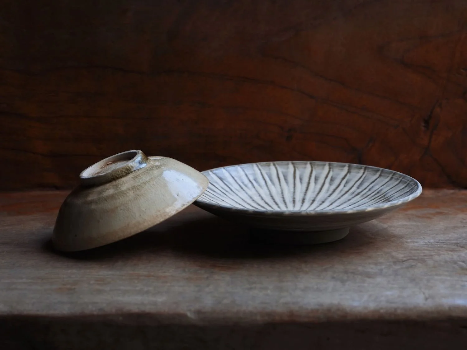 Set of plate and cup stacked together, with the top plate resting off-center to highlight its crackled glaze and historic foot ring of the Vietnamese Le period vessel