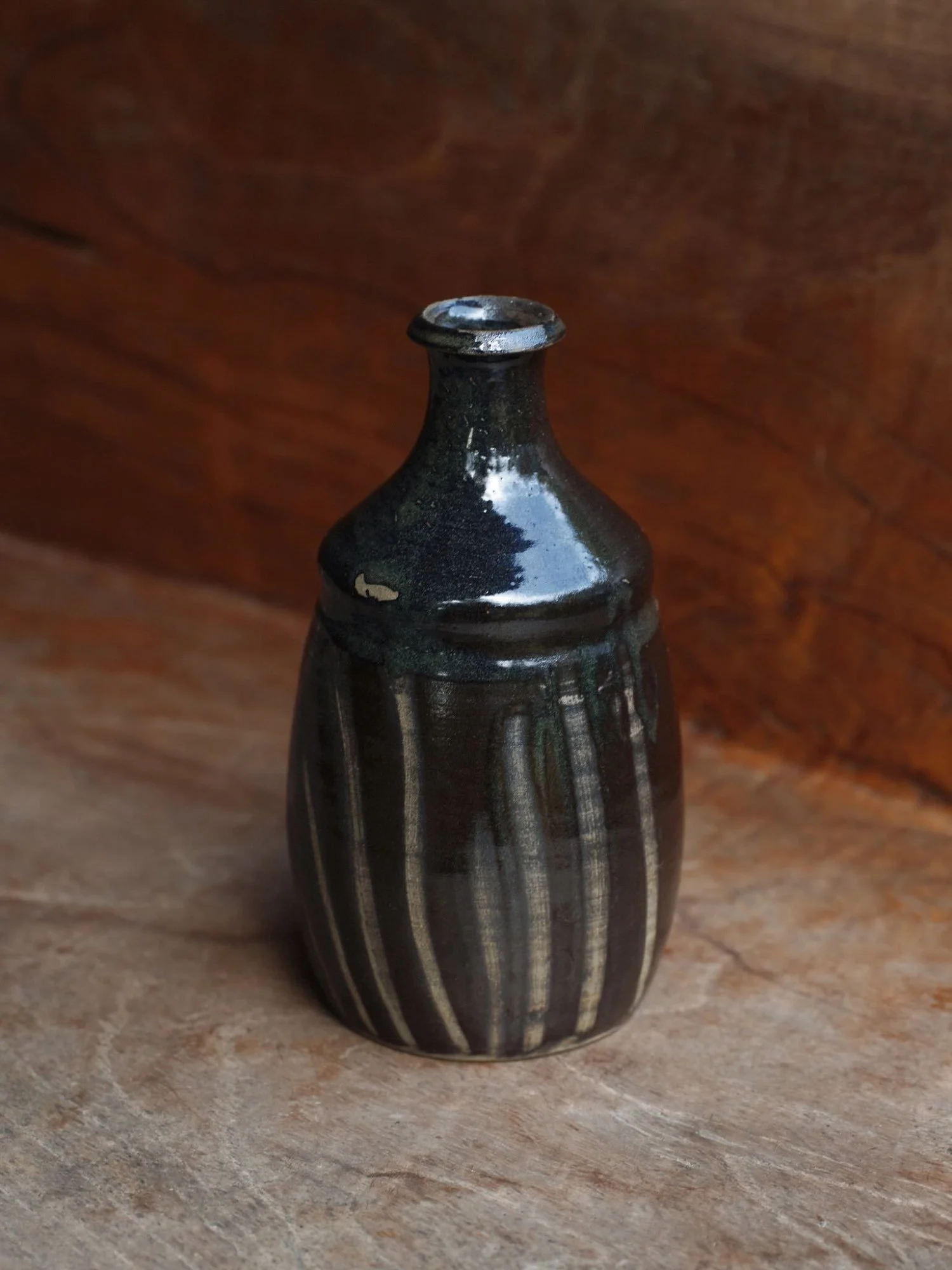 Black pottery vessel from Japan, with cream coloured brushstrokes. Has a rustic feel, presented on a wooden shelf. maison tombo.