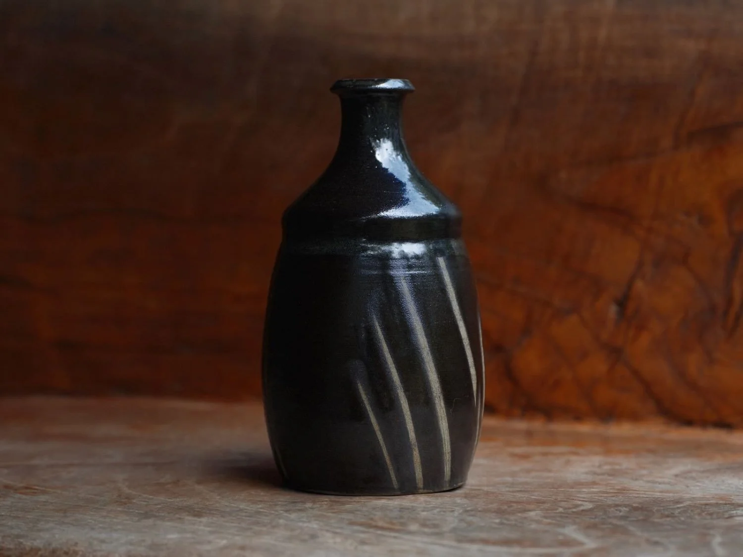 vessel shaped as a bottle or vase in colour black with cream brushstrokes presented on a wooden shelf - from Onta Village, Japan