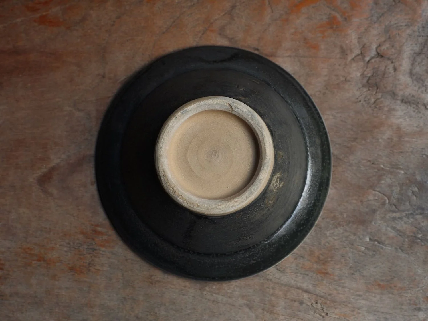 Dark blue ceramic bowl with ringed rim on a rustic wooden table.