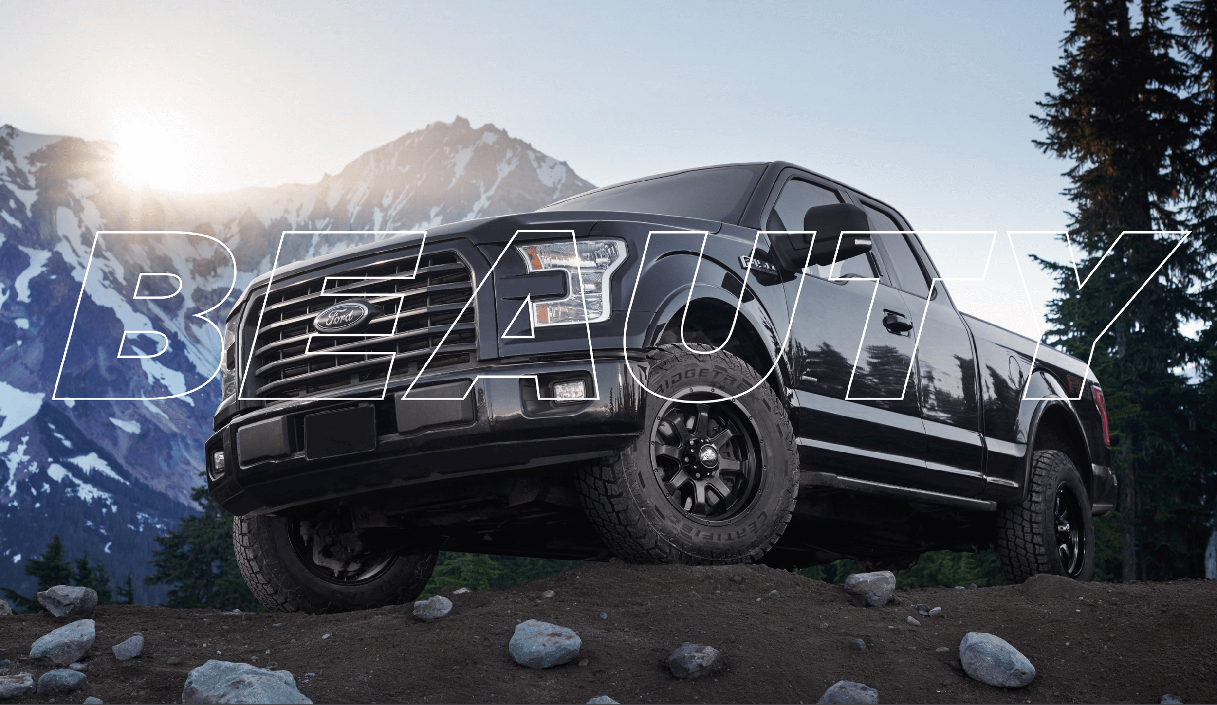 Beauty shot of a black truck and tires with a mountain in the background.