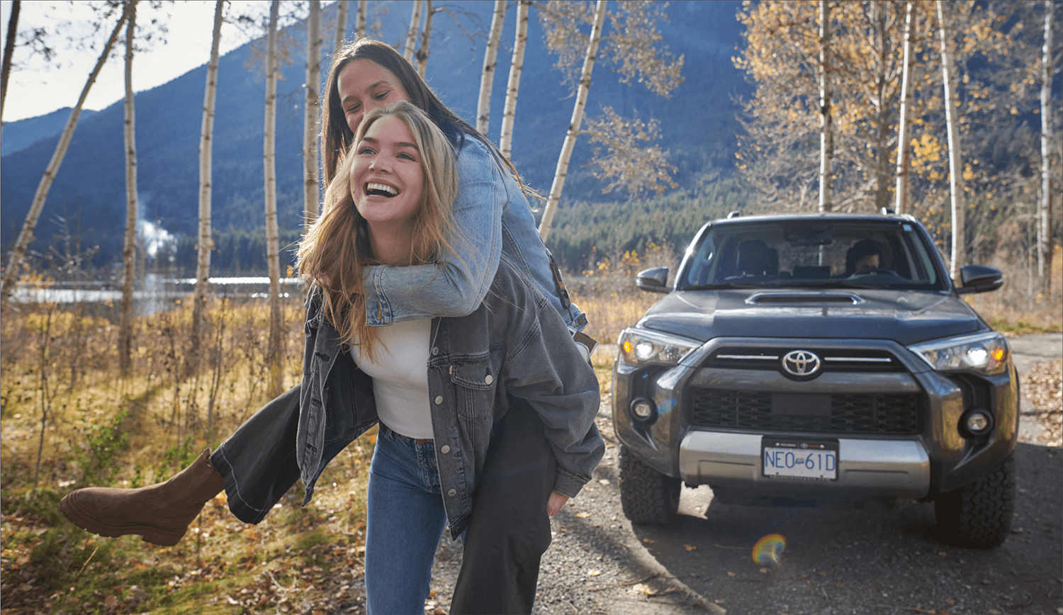 Two girls outside, one giving a piggyback ride to the other.