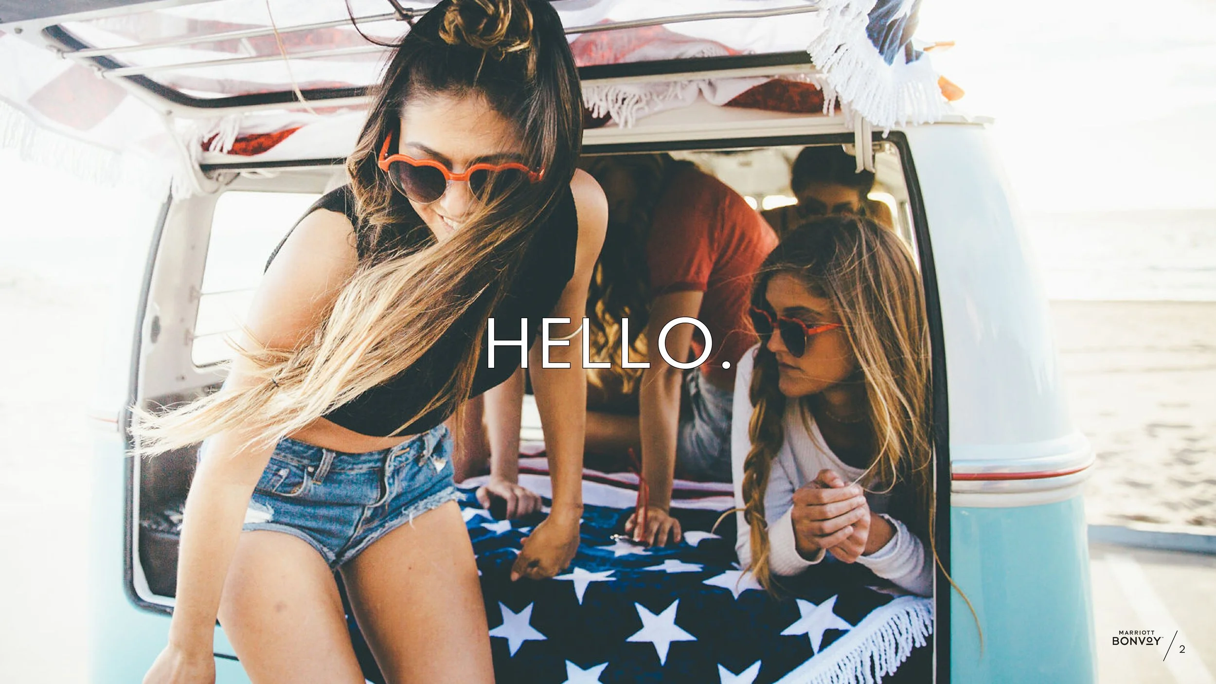 A woman with heart sunglasses is getting out of the back of a retro van