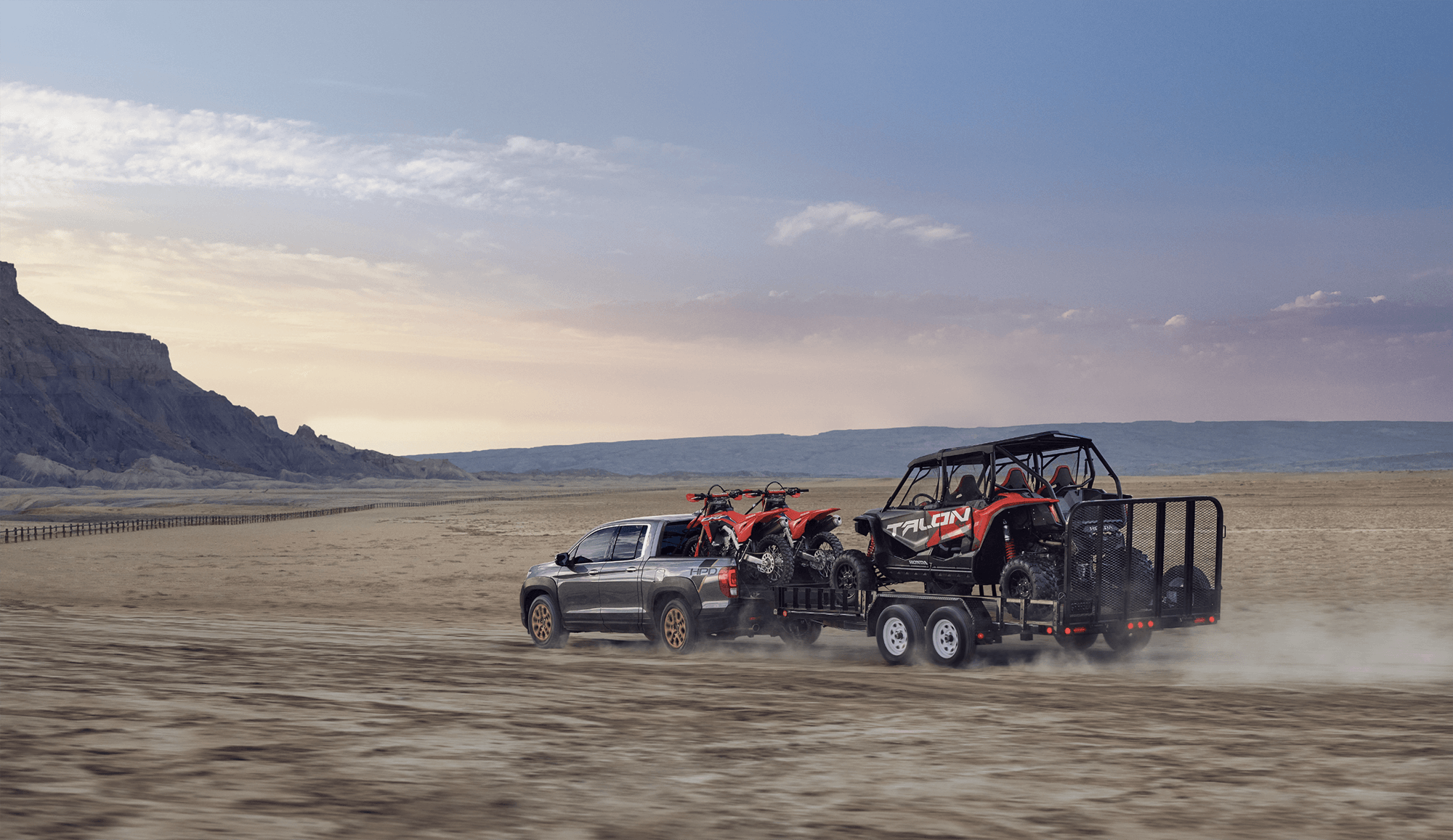 Truck hauling several recreational vehicles through the desert