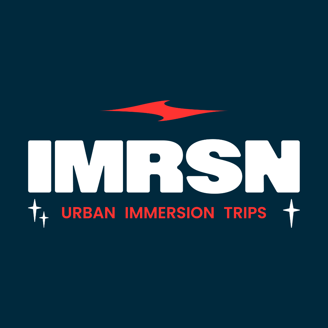 Logo for IMRSN Urban Immersion Trips, featuring a red stylized arrow or lightning bolt above the bold white letters 'IMRSN' and red text 'Urban Immersion Trips' with star icons on each side.