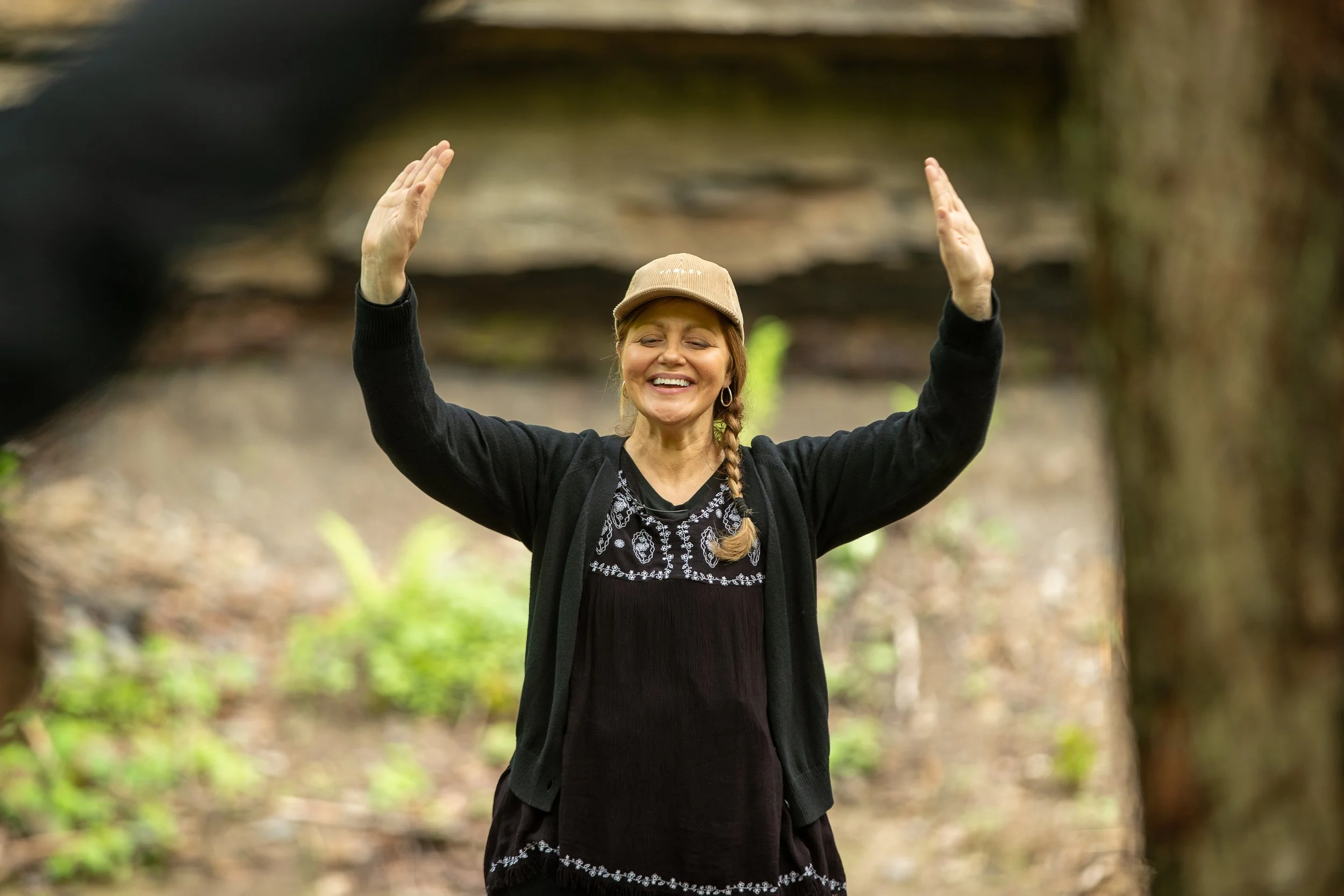 image of a girl smiling by raising hand in forest bath.