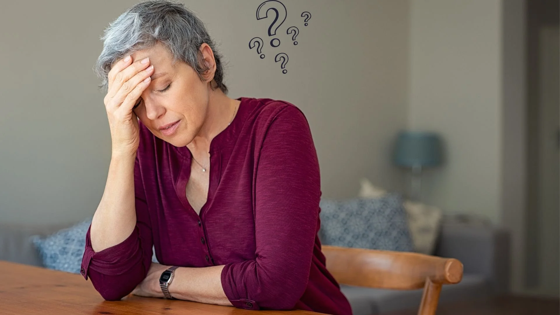 Woman sitting at table feeling confused and disconnected, holding her head in her hands