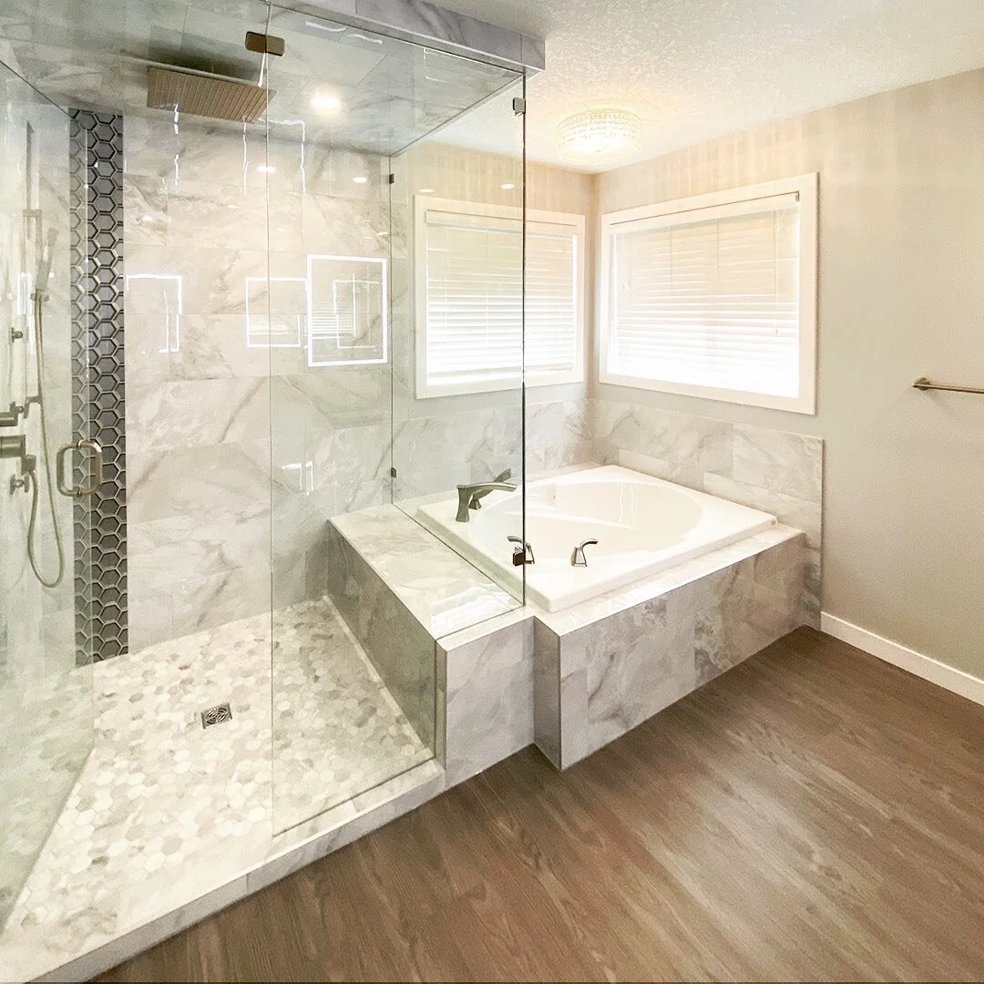 This gorgeous custom bathroom in Airdrie is now finished! A complete configuration of this bathroom allowed space for an oversized custom-tiled shower with rain components, large soaker tub, water closet space, double vanity and premium lighting. 

#