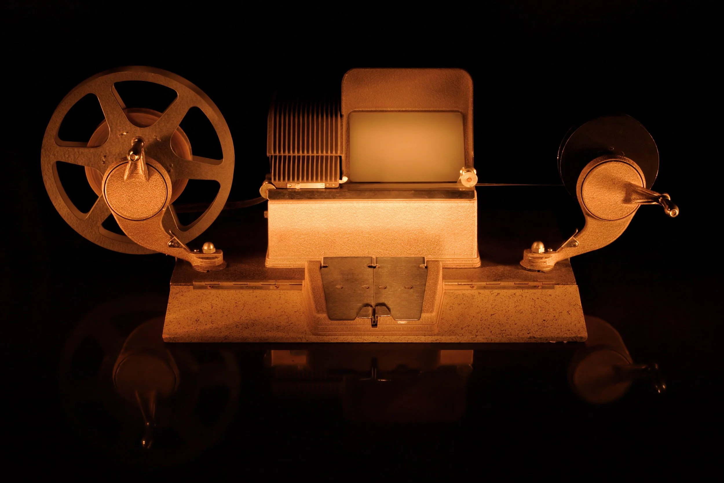 A vintage film projector with a black background and a warm glow.