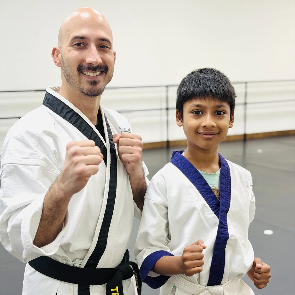Taekwondo Instructor with a student posing with hands up in karate uniforms.