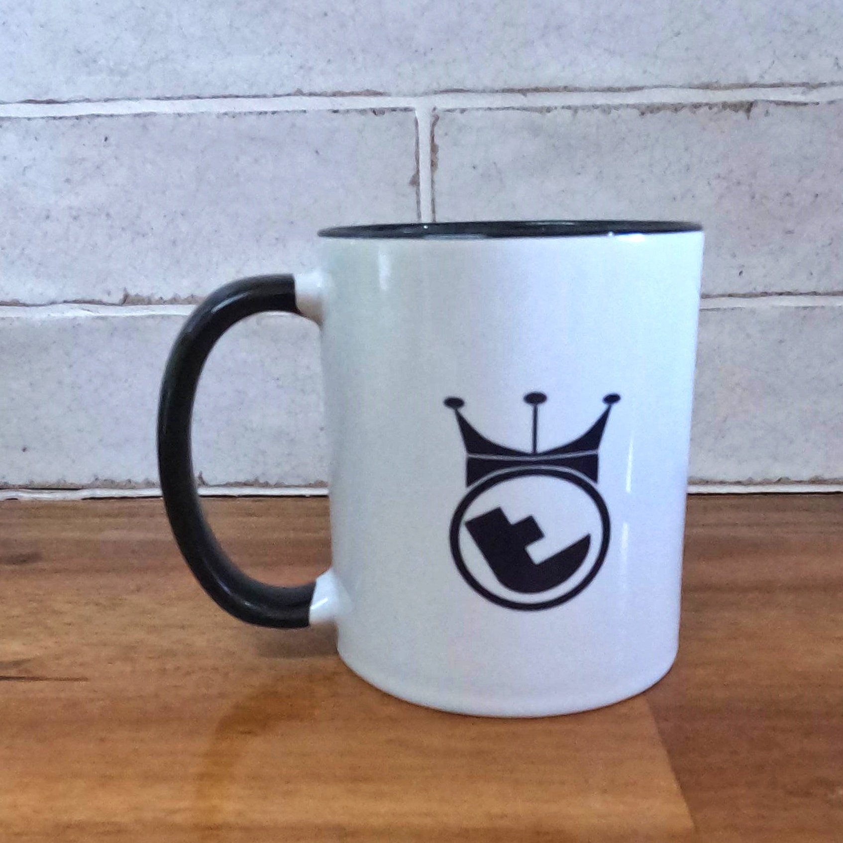 TwistedBends logo on white mug with black handle on wooden bench.