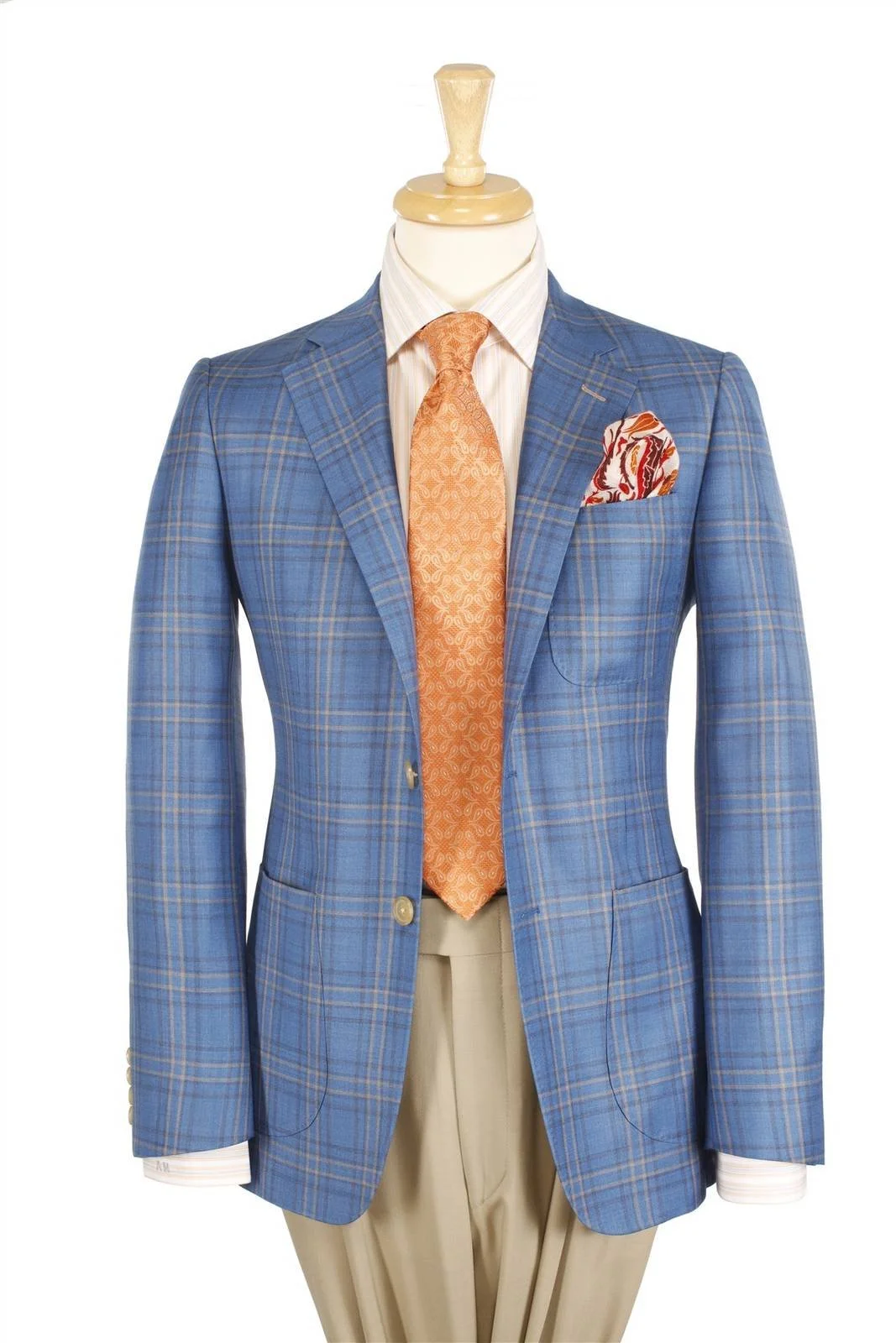 Blue plaid sport coat with orange tie and patterned pocket square over tan trousers