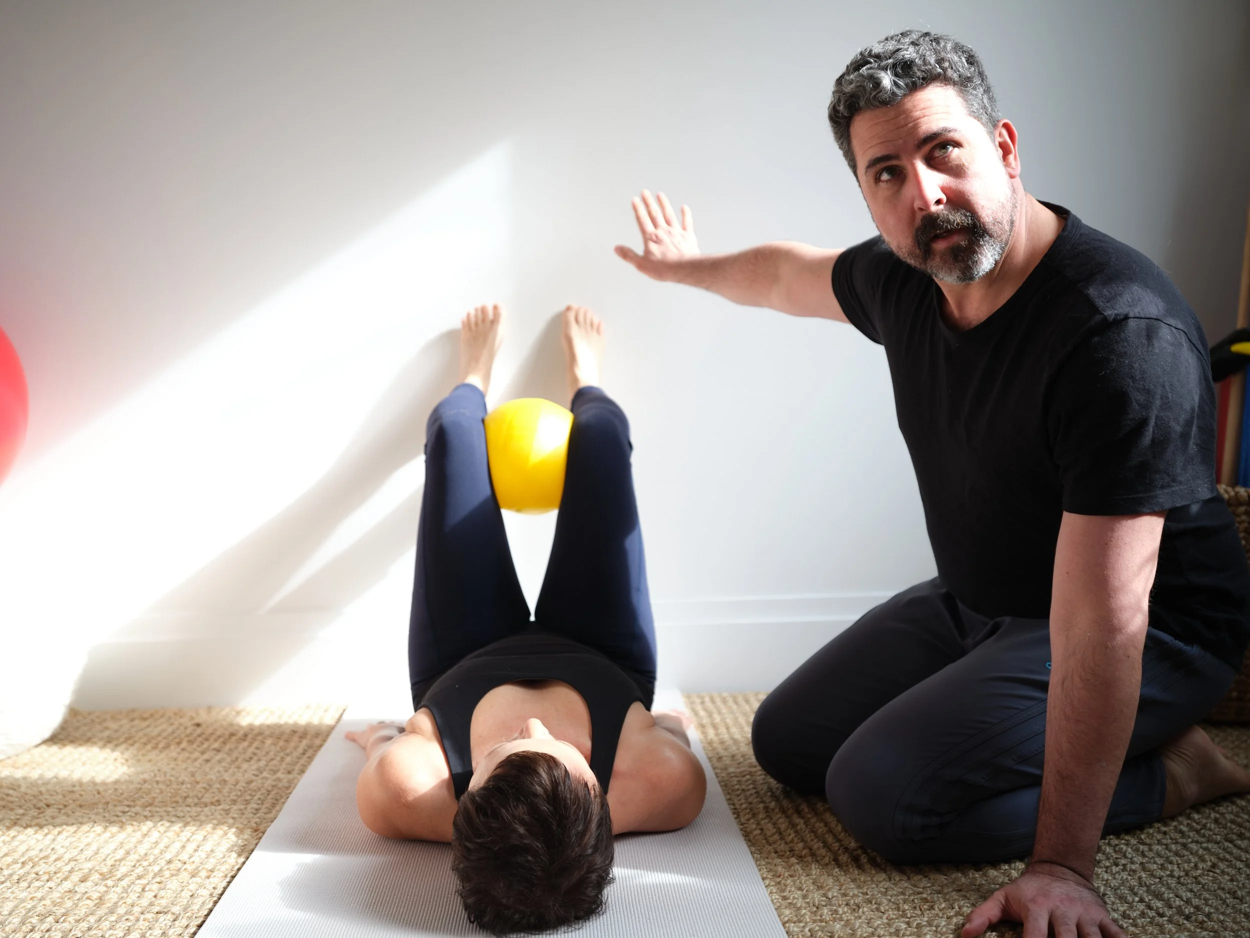 Two Pilates teachers sitting on Pilates equipment