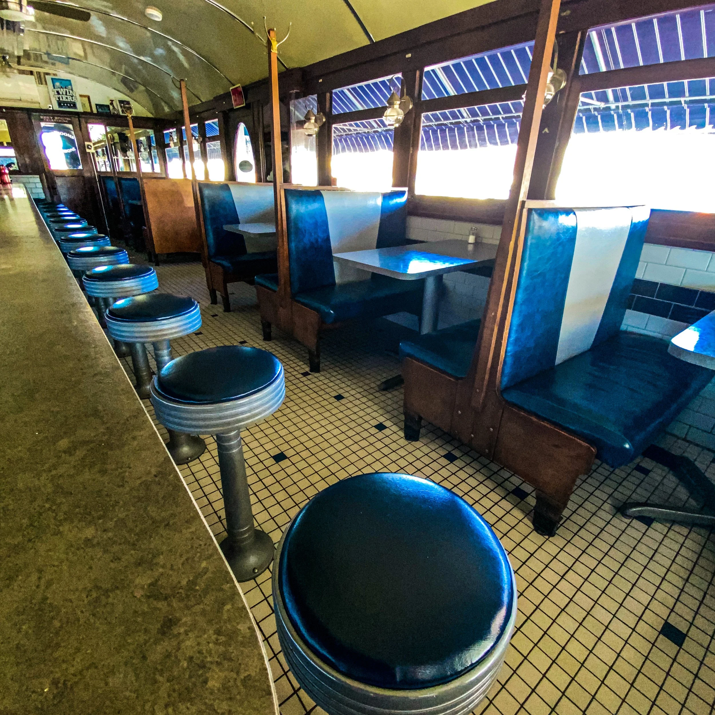 Interior of a vintage-style diner with booth seating and counter stools.