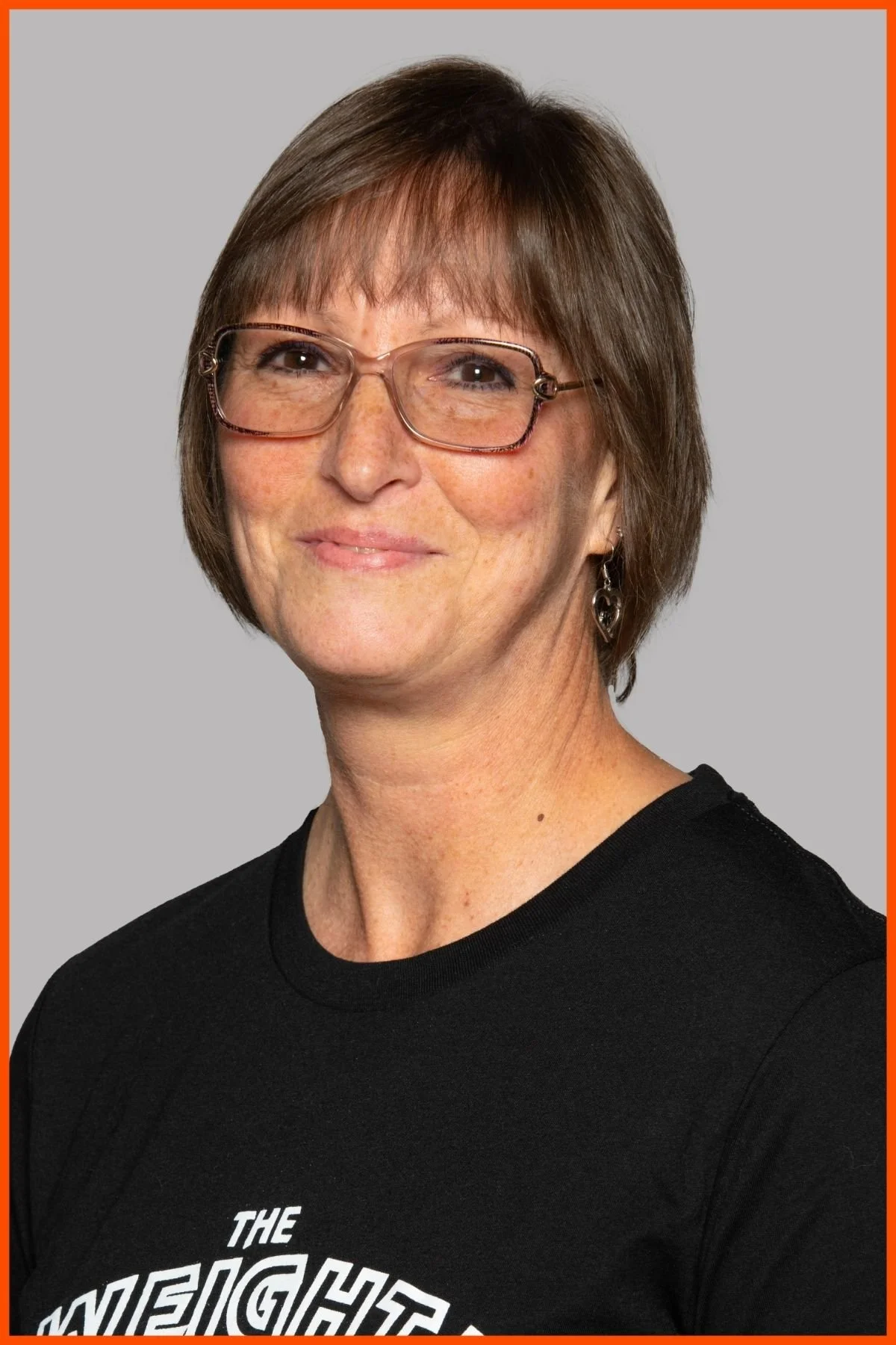 A portrait of The Weight Club front desk supervisor, Donna Brillhart, wearing a black weight club shirt with The Weight Club logo.