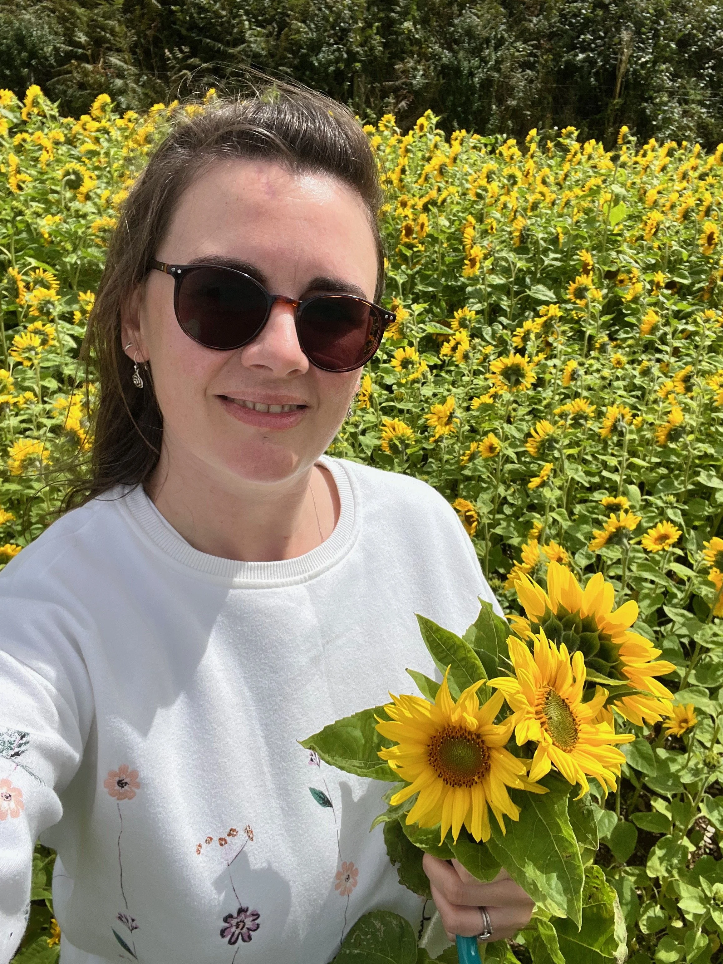 flower preservation artist in a sunflower field holding sunflowers