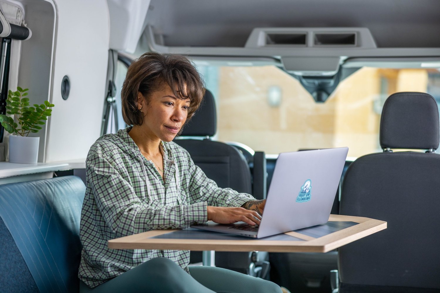 Woman using a laptop at a table inside a camper van or RV.