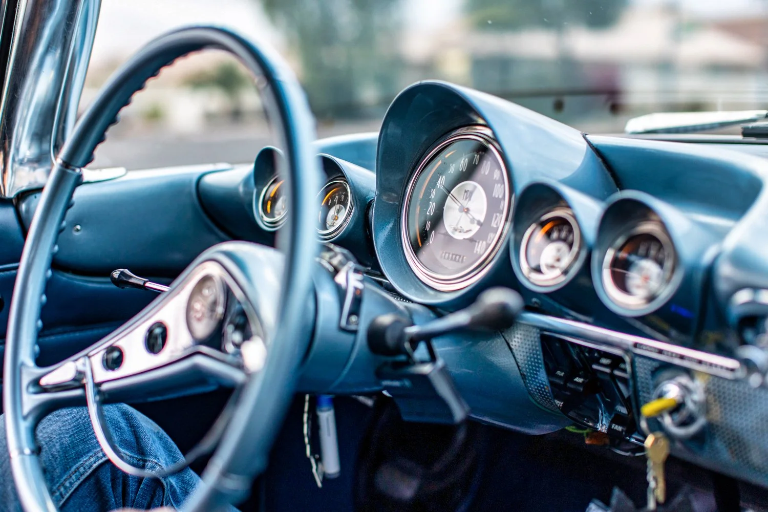 Close-up of the dashboard and steering wheel of a vintage car, showing gauges and speedometer.