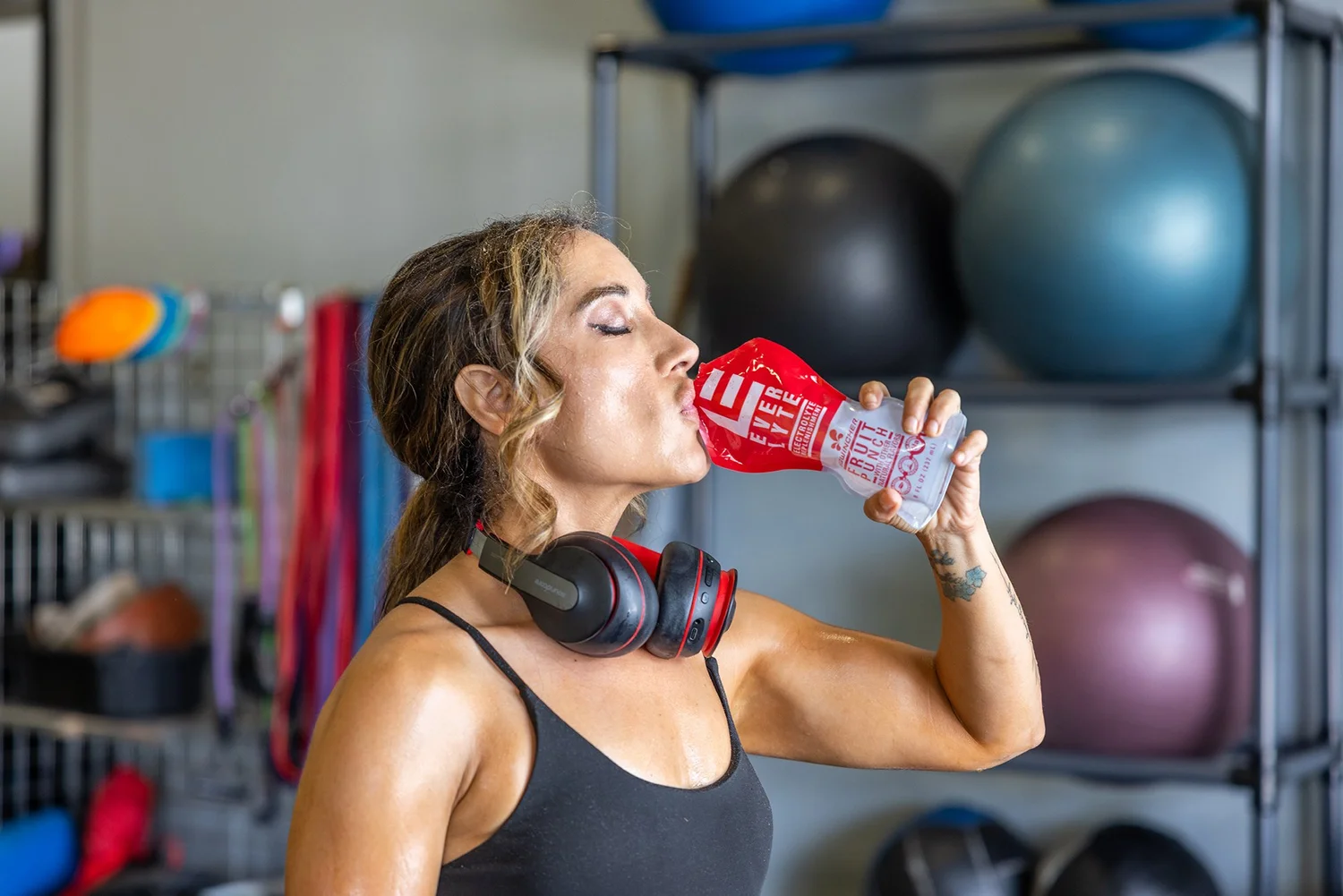 Athlete drinking Sqwincher in a home gym