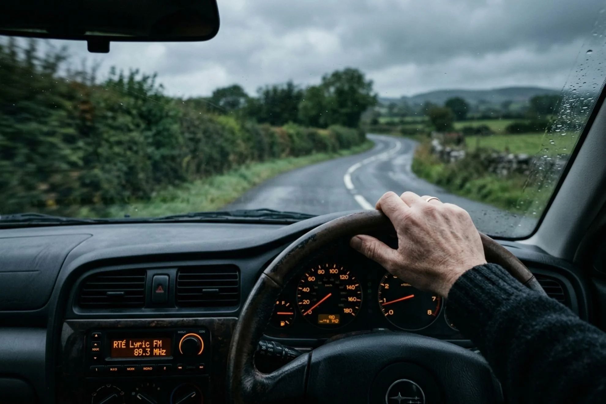 Driver's view from inside a car on a wet Irish country road, RTÉ Lyric FM showing on the dashboard radio display