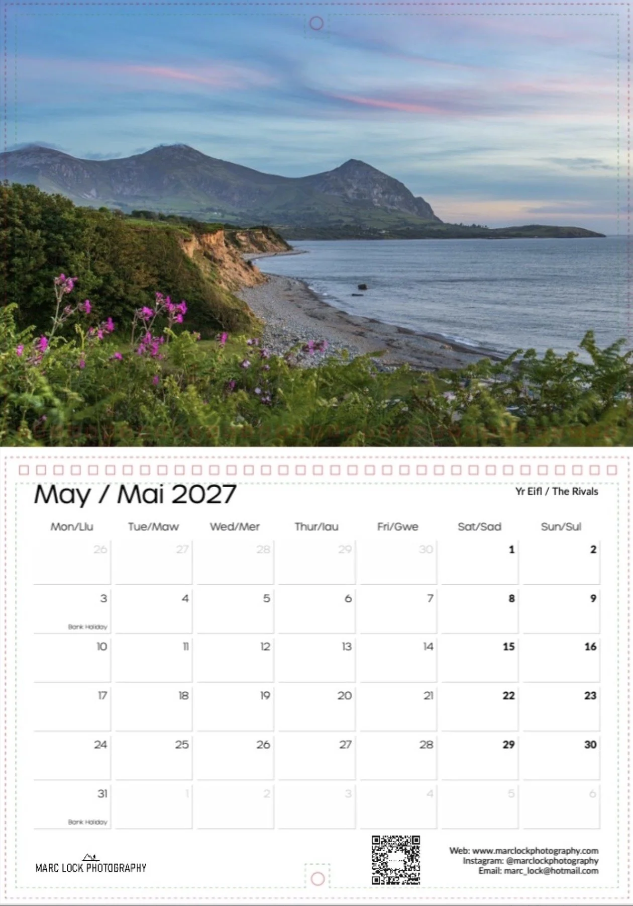 A scenic landscape of mountains, coastline, and water with a sky at dusk or dawn, featuring pink and blue clouds, seen above a May 2023 calendar page.