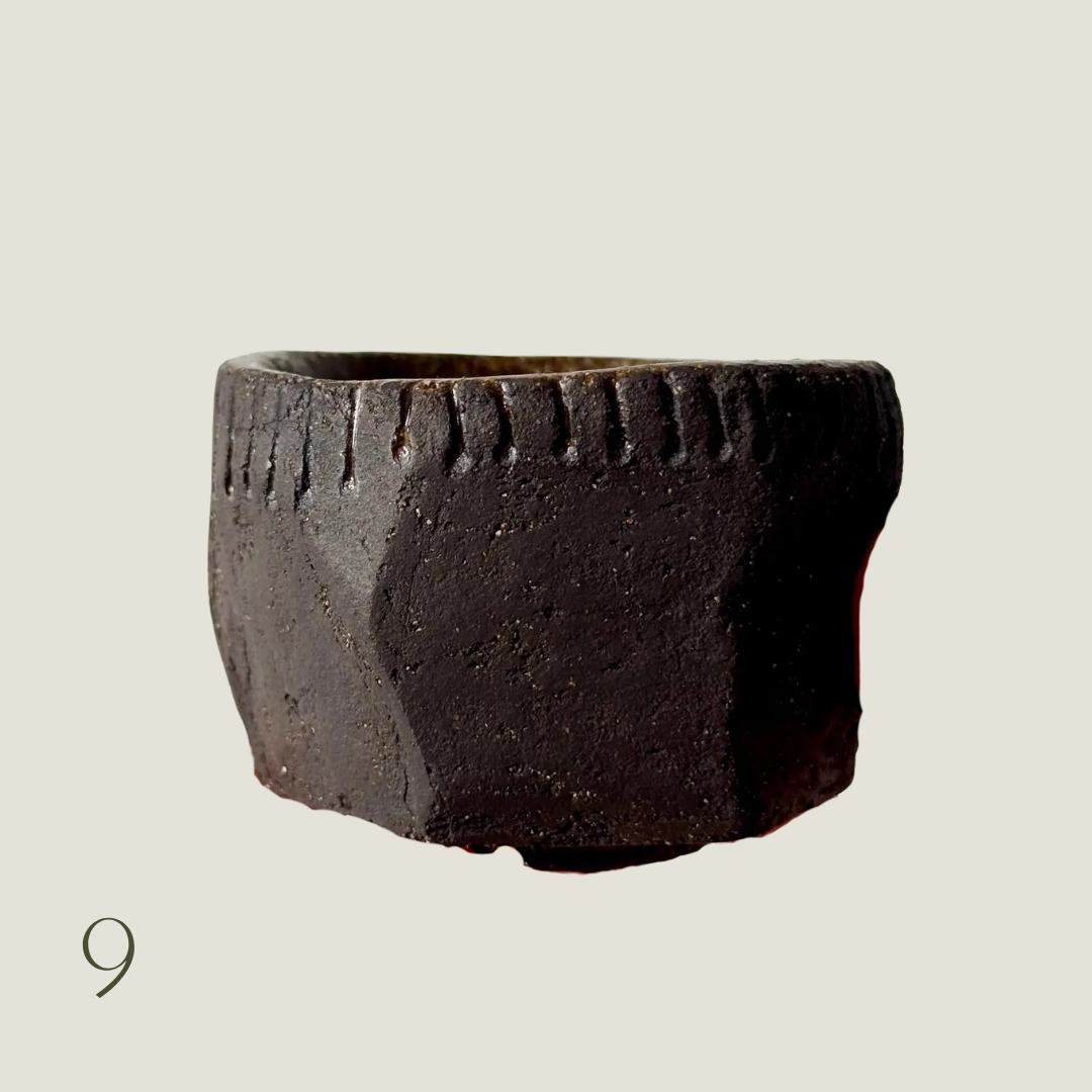 Handmade rustic black ceramic vessel with faceted sides and an incised rim