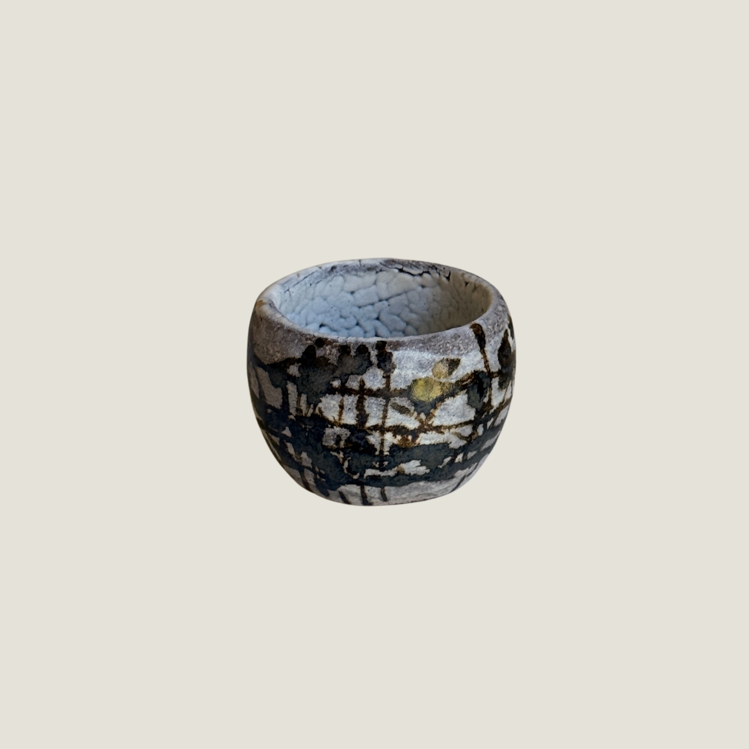 Round ceramic cup with white crackle glaze, black splatter and grid-like brush marks, pale crackled interior