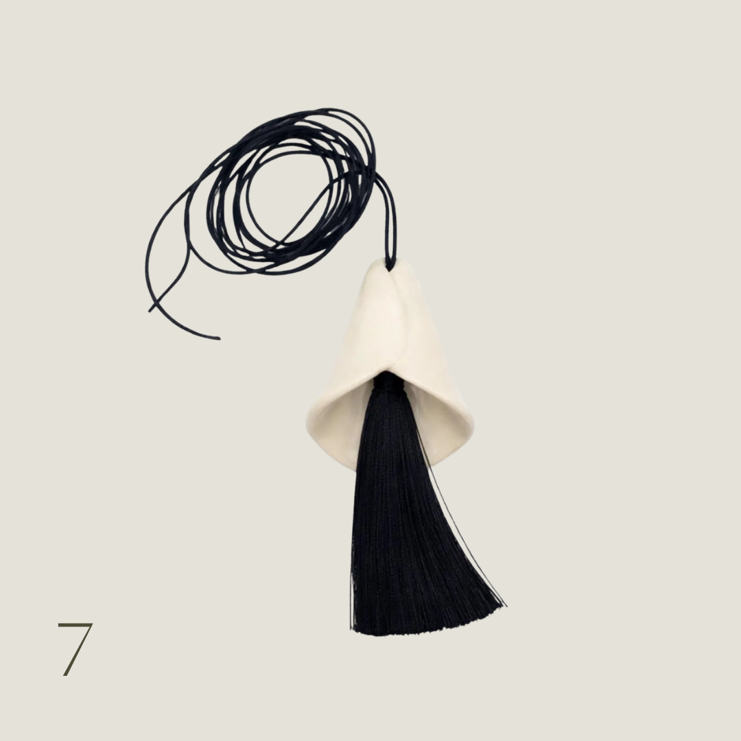 Cream calla lily pendant necklace with a black tassel on a long black cord