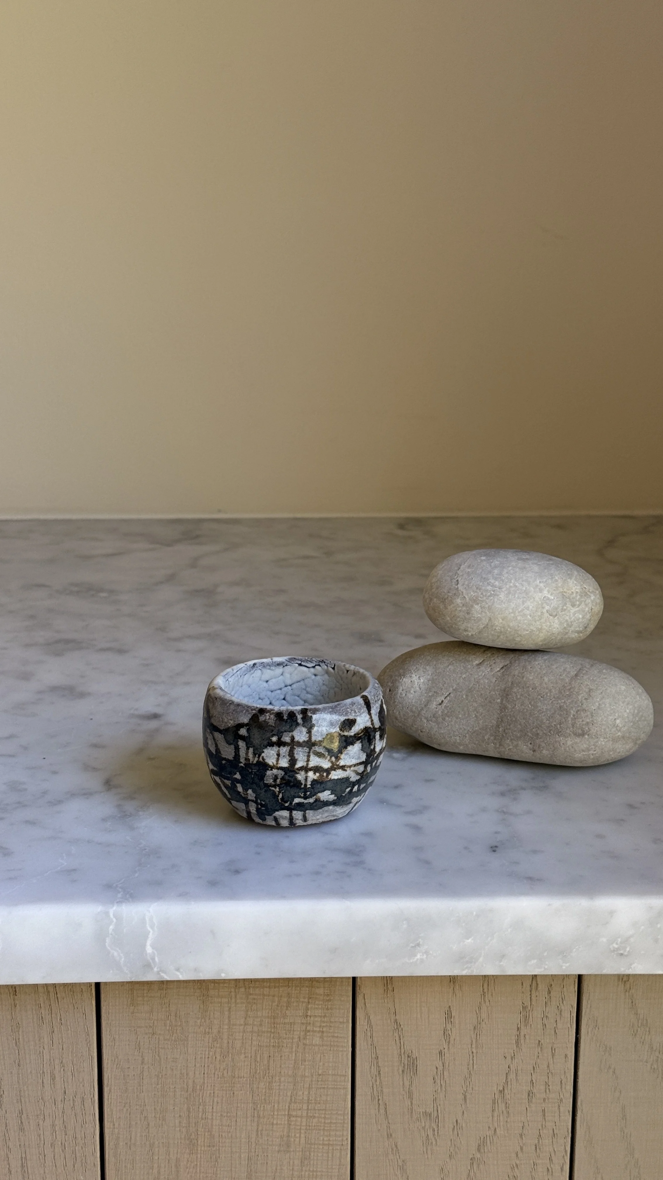 Round ceramic cup with white crackle glaze, black splatter and grid-like brush marks, and a small gold accent, pale crackled interior