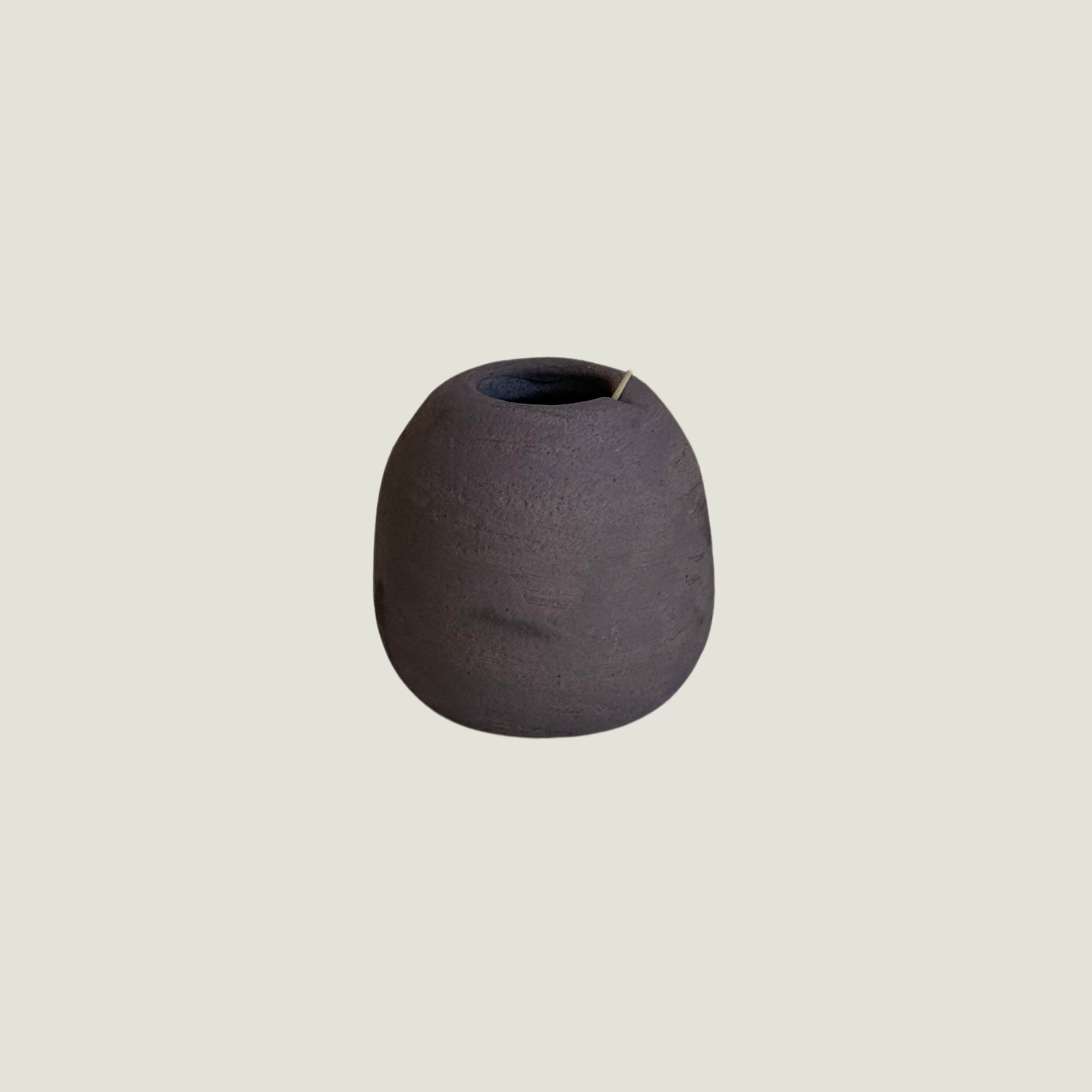 Small round matte brown ceramic bud vase with a narrow opening and a soft hand-pressed dimple on one side